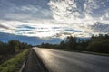 Asphalt road in bright back sunlight in the early cloudy morning. Royalty Free Stock Photo