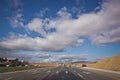 Asphalt road and bright blue sky with fluffy clouds . Empty desert asphalt road from low angle with mountains and clouds on Royalty Free Stock Photo