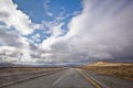 Asphalt road and bright blue sky with fluffy clouds . Empty desert asphalt road from low angle with mountains and clouds on Royalty Free Stock Photo