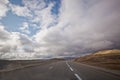 Asphalt road and bright blue sky with fluffy clouds . Empty desert asphalt road from low angle with mountains and clouds on Royalty Free Stock Photo
