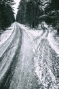 Asphalt road covered with snow leading through the forest. Winter scenery shown in black and white Royalty Free Stock Photo