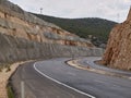 Asphalt road curves between two rock cliffs with openwork power line pillars atop