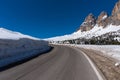 Asphalt road in the Dolomites in the spring. Mountains and forests against a blue sky