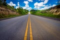 Asphalt road through the field and clouds on blue sky