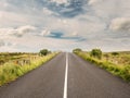 Asphalt road goes to horizon line, Colorful cloudy sky. Green fields on each side Royalty Free Stock Photo