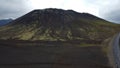 Asphalt road going by a green moss-covered volcanic mountain and black lava field in Iceland Royalty Free Stock Photo