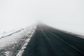 Asphalt road going through a snowy field