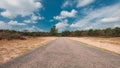 An asphalt road leading to the horizon, under a blue sky with clouds, in The Loonse and Drunense Duinen National Park Royalty Free Stock Photo