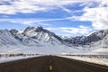 Asphalt road leading to the snow-covered mountains range of Sierra Nevada in winter Royalty Free Stock Photo