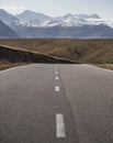 Asphalt road with markings in the mountains against the background of a valley and a mountain range with snow cover and glaciers Royalty Free Stock Photo