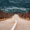 Asphalt road panorama in countryside on cloudy day. Road in forest under dramatic cloudy sky.