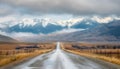 asphalt road on the prairie goes beyond horizon to the high mountains