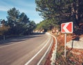 Asphalt road with road sign in the forest at sunrise Royalty Free Stock Photo