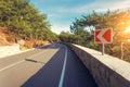 Asphalt road with road sign in the forest at sunrise Royalty Free Stock Photo