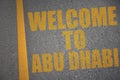 asphalt road with text welcome to Abu Dhabi near yellow line