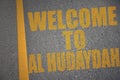 asphalt road with text welcome to Al Hudaydah near yellow line