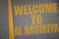 asphalt road with text welcome to Al Nasiriyah near yellow line Royalty Free Stock Photo