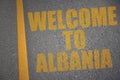 asphalt road with text welcome to albania near yellow line.