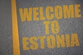 asphalt road with text welcome to estonia near yellow line.