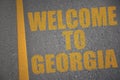 asphalt road with text welcome to georgia near yellow line
