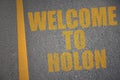 asphalt road with text welcome to Holon near yellow line