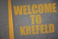 asphalt road with text welcome to Krefeld near yellow line