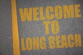 asphalt road with text welcome to Long Beach near yellow line Royalty Free Stock Photo