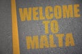 asphalt road with text welcome to malta near yellow line.