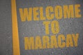 asphalt road with text welcome to Maracay near yellow line