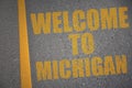 asphalt road with text welcome to michigan near yellow line.