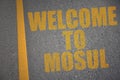 asphalt road with text welcome to Mosul near yellow line