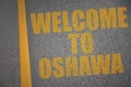 asphalt road with text welcome to Oshawa near yellow line