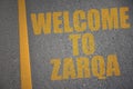 asphalt road with text welcome to Zarqa near yellow line