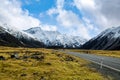 On the asphalt road to the big and tall Mountains  in winter, dry grass turns yellow in blue skies and beautiful clouds Royalty Free Stock Photo