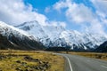 On the asphalt road to the big and tall Mountains  in winter, dry grass turns yellow in blue skies and beautiful clouds Royalty Free Stock Photo