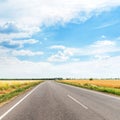 Asphalt road to horizon in field and clouds Royalty Free Stock Photo