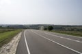 Asphalt road with white markings going through hilly countryside. Royalty Free Stock Photo