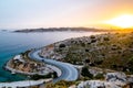 Asphalt serpentine road, park with mountains and rocks and sea with sunset on the background. Travel in Athens, Greece Royalty Free Stock Photo