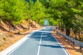 Asphalt serpentine road in Troodos mountain range with roadside fence and trees