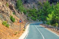 Asphalt serpentine road in Troodos mountain range with roadside fence and trees
