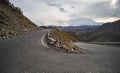 The asphalt serpentine track winds and turns along the mountain slope against the backdrop of a mountain range with snow Royalty Free Stock Photo