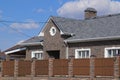 Asphalt shingle. Decorative bitumen shingles on the roof of a brick house. Fence made of corrugated metal. Royalty Free Stock Photo