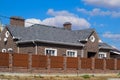 Asphalt . Decorative bitumen shingles on the roof of a brick house. Fence made of corrugated metal