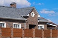 Asphalt . Decorative bitumen shingles on the roof of a brick house. Fence made of corrugated metal Royalty Free Stock Photo