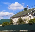 Asphalt shingle. Decorative bitumen shingles on the roof of a brick house. Fence made of corrugated metal.