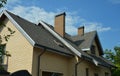 An asphalt shingled roof with skylights, attic windows, chimneys, fascias, and a roof gutter. A close-up of a gray double-pitched Royalty Free Stock Photo