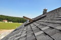 Asphalt shingles roof with open attic skylight window and unfinished roof chimney Royalty Free Stock Photo