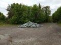 Asphalt street with pile of grey rocks or stones and trees