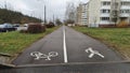 Asphalted sidewalks and a bike path are laid between the carriageway of the street with parked cars and residential buildings. Shr