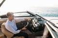 Aspirational successful businessman standing by luxury boats and yachts against a deep blue sky, holding his jacket over Royalty Free Stock Photo